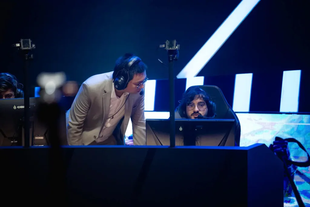 Coach SeeEl e Guigo conversando durante os picks e bans do jogo no CBLOL 2024