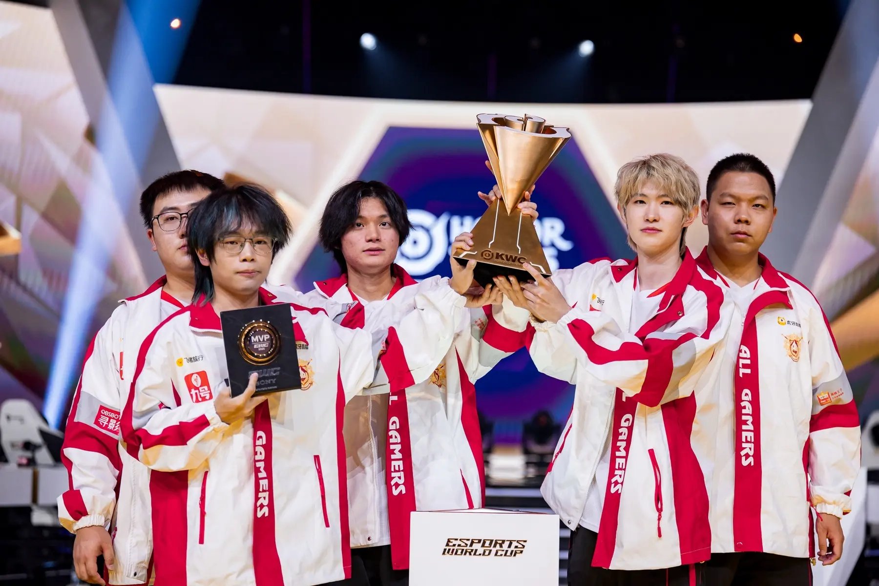 Members of the All Gamers esports club holding a gold trophy and an MVP award at the Esports World Cup.