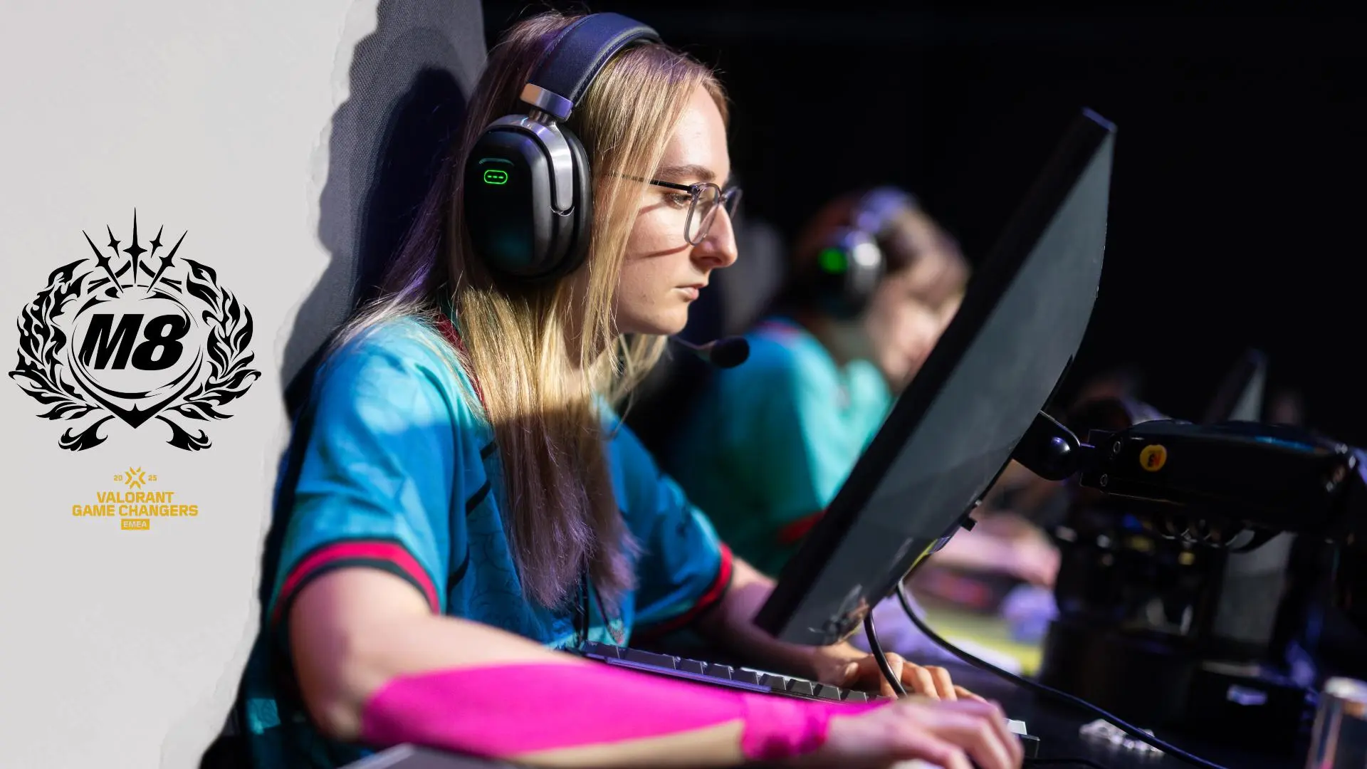 A female gamer wearing a headset and teal jersey competing at a Valorant Game Changers event.