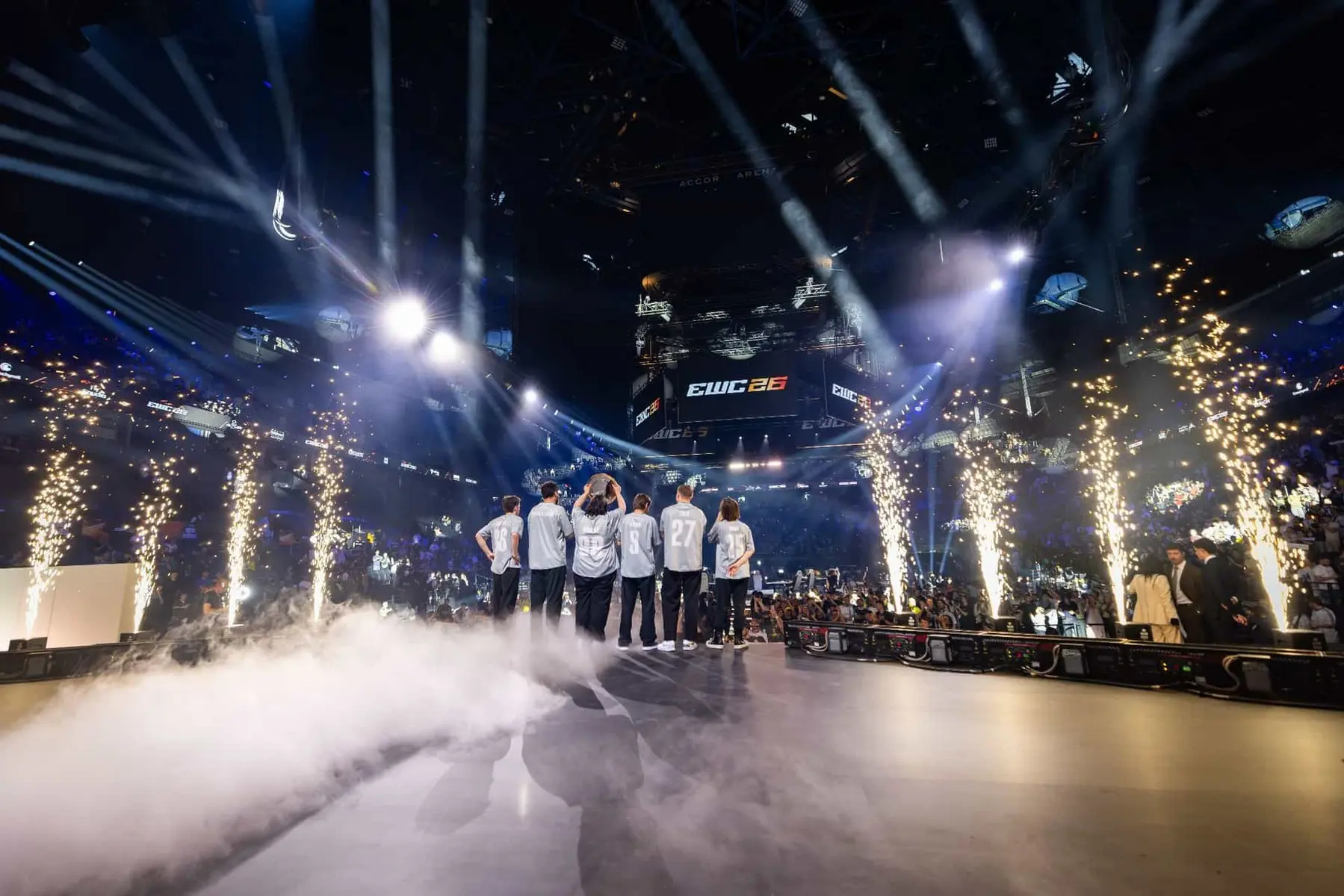 Team Spirit players standing on stage at the Accor Arena during the EWC 2024 event with fireworks and smoke.