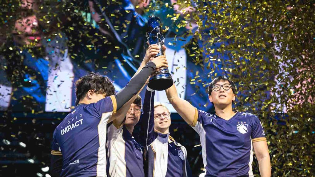 Team Liquid players lift a championship trophy on stage surrounded by gold confetti.