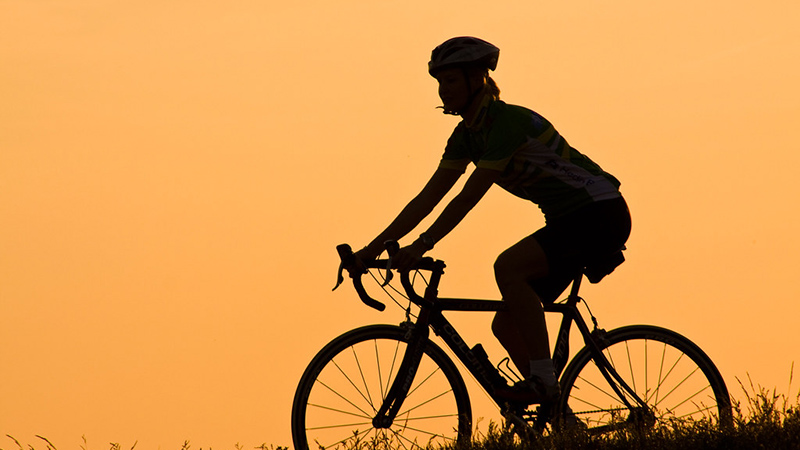 image of a person riding a bicycle at sunset