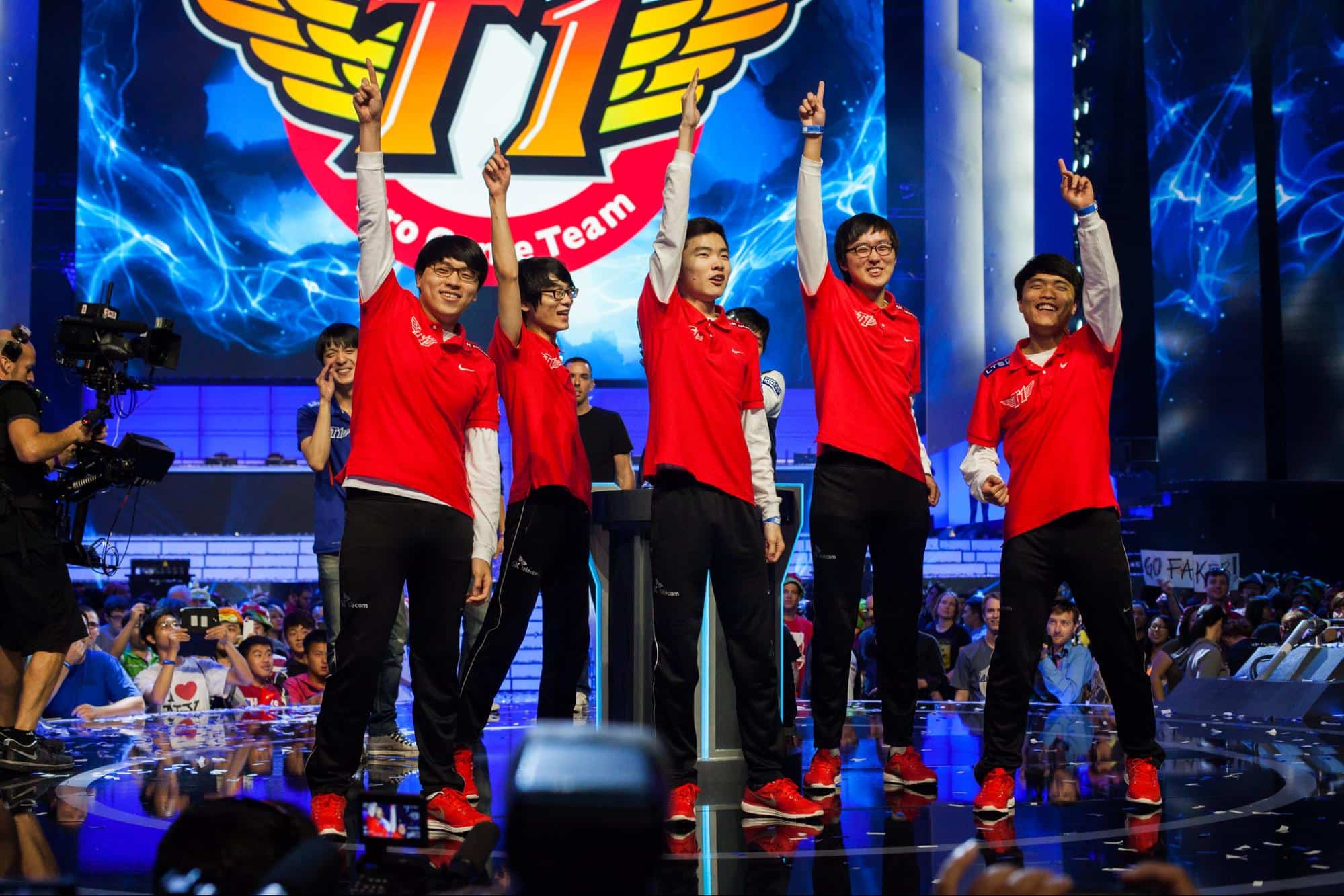 T1 players celebrating on Worlds stage in red jerseys