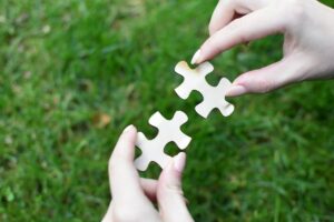Two pieces of a jigsaw against a green background being pieced together.