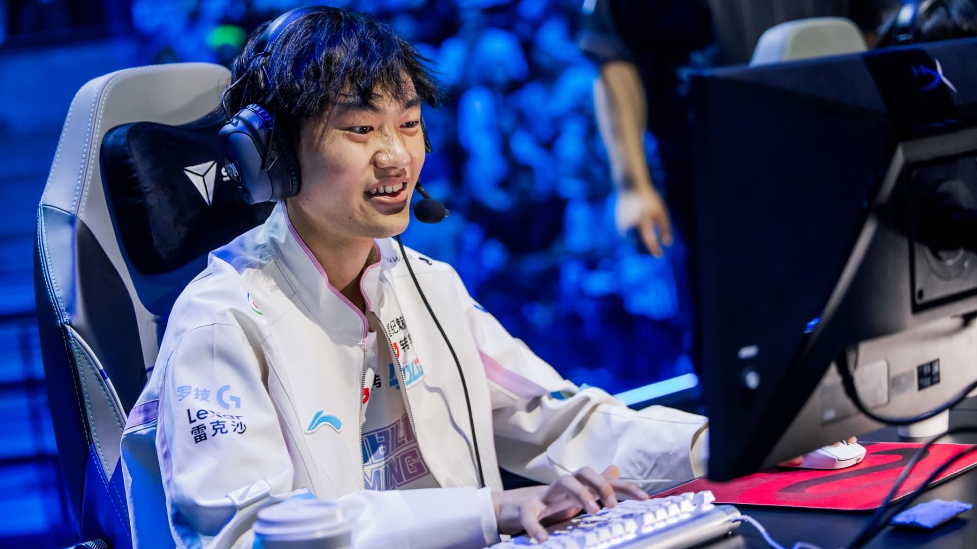 BLG Knight smiling while playing on stage in team jacket and headset