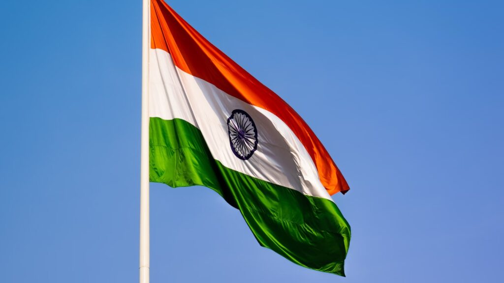 India flag blowing in wind with blue sky in background