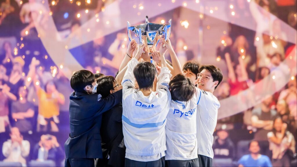DRX League of Legends players celebrate their Worlds 2022 victory by lifting the Summoner’s Cup on stage as confetti falls around them