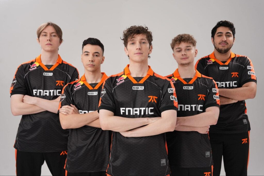 FNATIC’s esports roster posing for a team photo in black and orange jerseys with arms crossed, showcasing their official 2025 lineup against a neutral studio background.