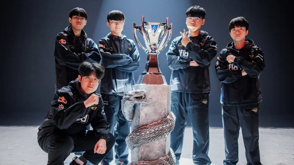 The League of Legends World Championship 2023 winning team standing proudly around the Summoner’s Cup, striking confident poses beside a stone pedestal entwined with a dragon sculpture.