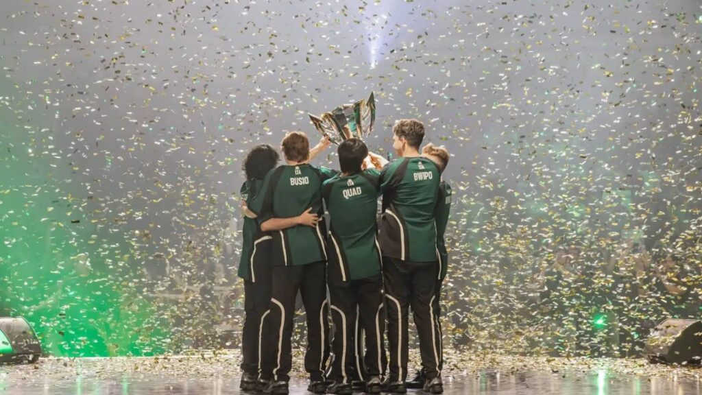 Esports team lifting a championship trophy amid falling confetti on stage