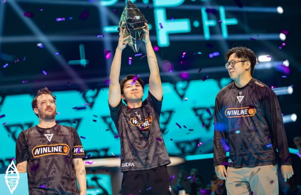 Players celebrate winning a Dota 2 event as a teammate lifts the tournament trophy on stage