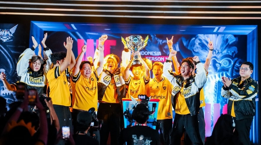 A victorious esports team in yellow jerseys lifting a large trophy on stage while cheering, surrounded by bright lights, cameras, and celebrating teammates during a MOONTON Games event