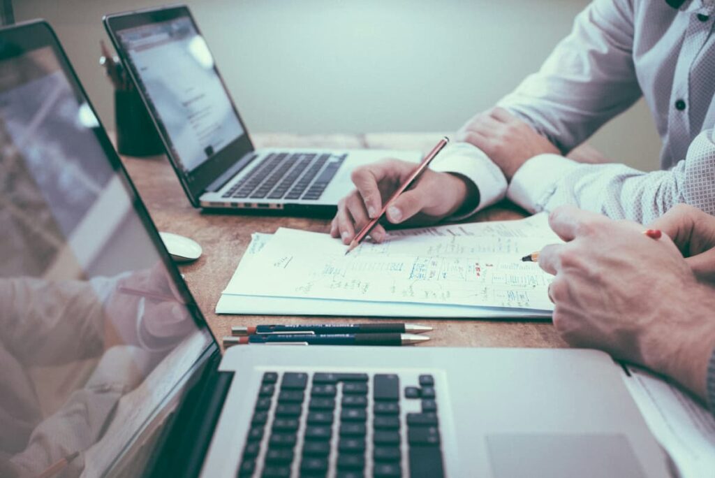 People working on financial results inbetween two laptops on a table
