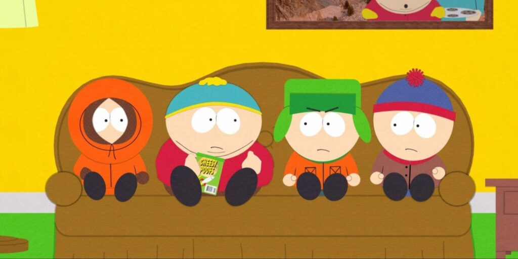 The four main South Park kids sitting on a brown couch in a bright yellow living room, with Cartman holding a bag of Cheesy Poofs