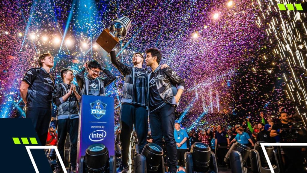 Players celebrate a major Dota 2 tournament win while lifting the trophy on stage