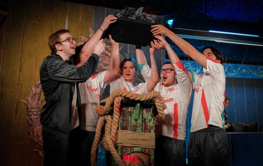 Players celebrate by lifting a trophy after a Dota 2 tournament victory