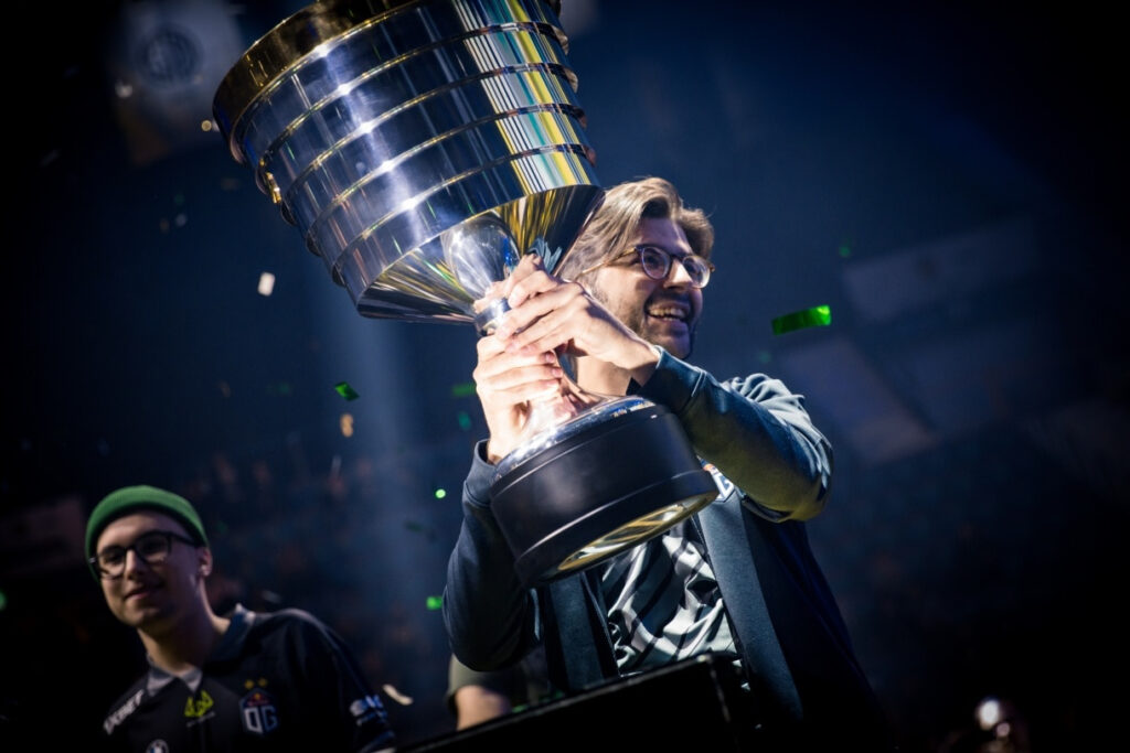 A player lifting the Aegis trophy on stage during a Dota 2 tournament celebration