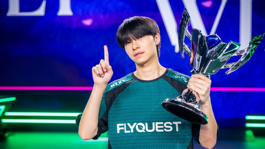A pro League of Legends player raises a trophy and gestures triumphantly during a 2025 event