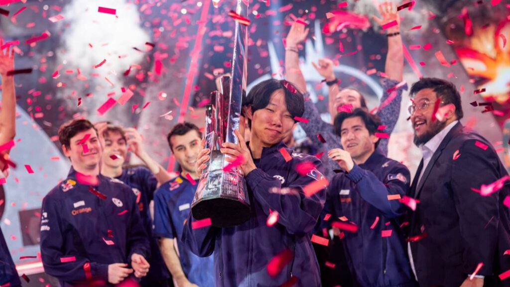 Team celebrating on stage as a player lifts the winner’s trophy