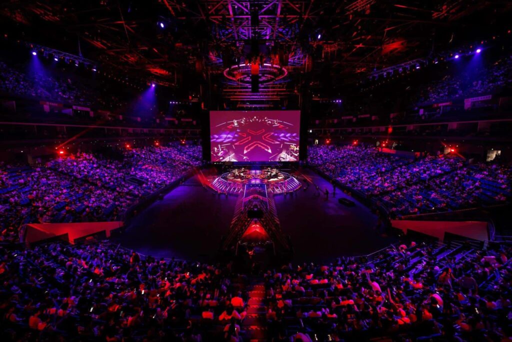 A sold-out esports arena hosts a large-scale live tournament with fans watching the main stage