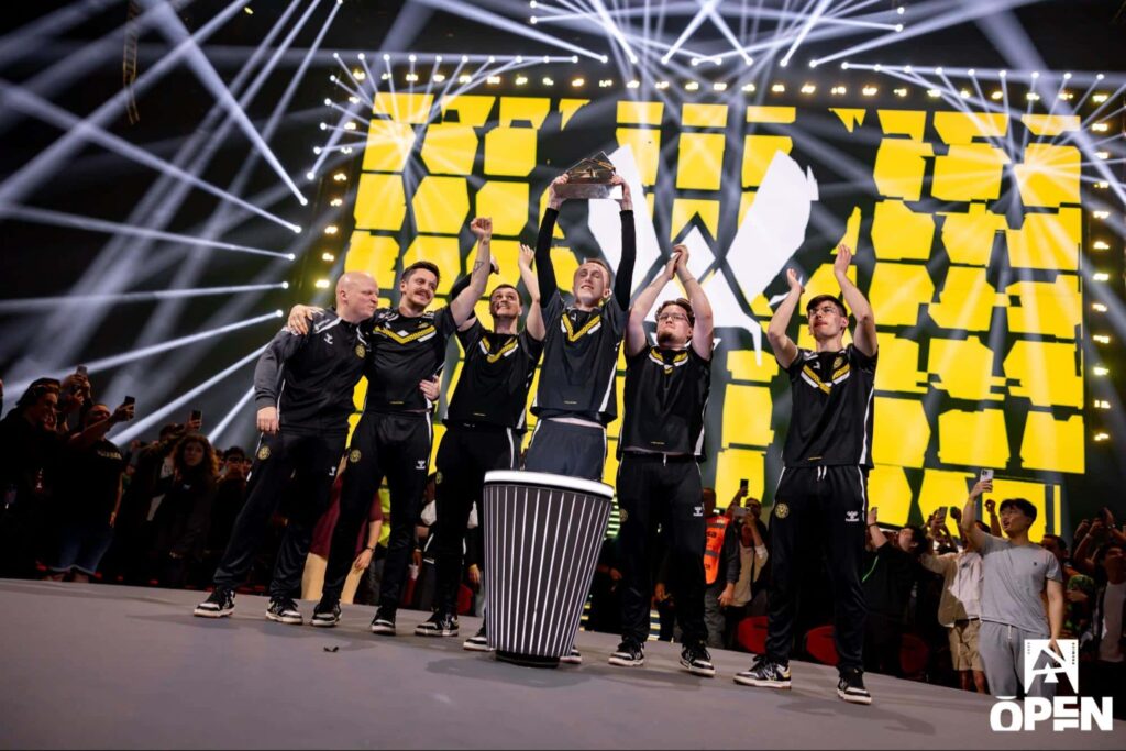 A Counter-Strike 2 team lifts the trophy on stage as fans cheer during a major LAN event