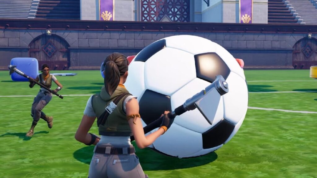 Two characters with tools approach a large soccer ball on a stadium field in a video game setting