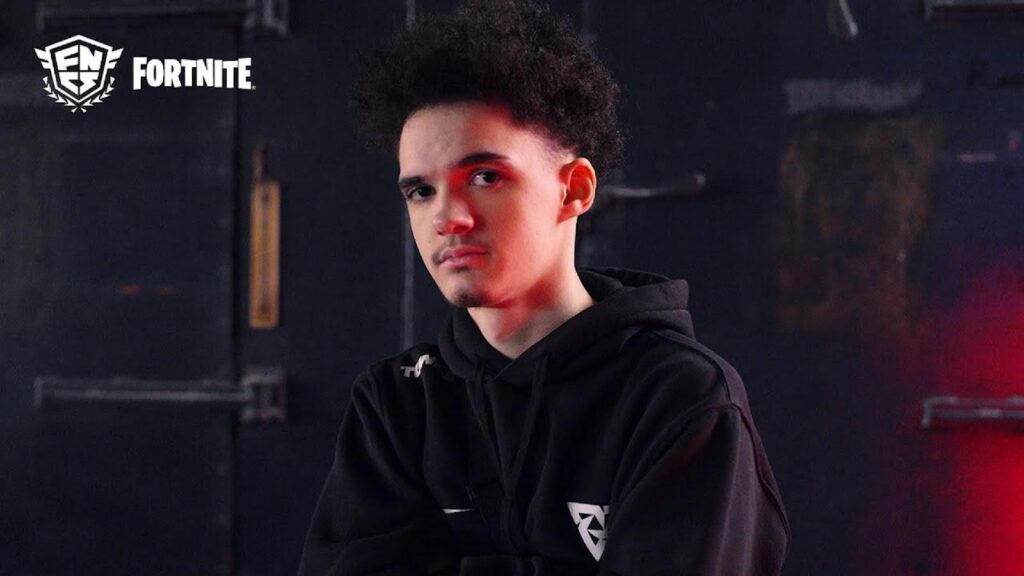 Fortnite professional player standing with arms crossed in a dark studio setting